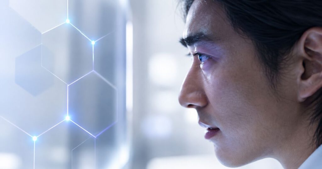 A focused man examines a futuristic digital interface with glowing hexagons, showcasing advanced technology.