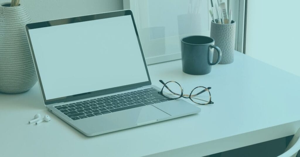 A sleek laptop on a desk with glasses and a coffee mug, creating a modern workspace atmosphere.
