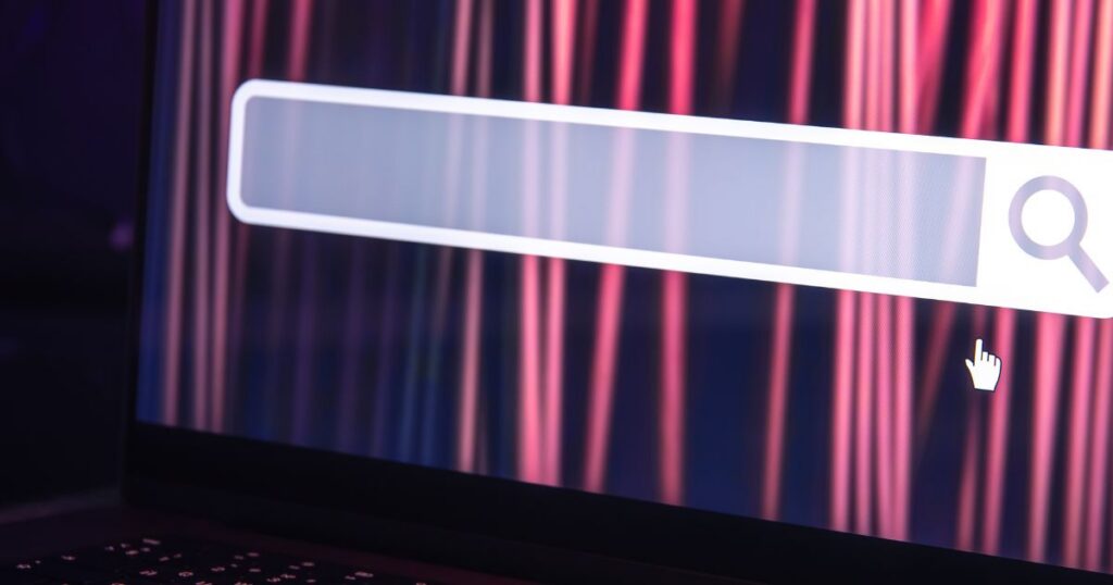 Close-up of a laptop screen displaying a blank search bar against a vibrant, abstract background.