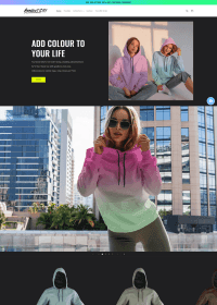 Woman wearing a gradient hoodie, holding the hood up, with a city skyline in the background. Bright, stylish fashion look.